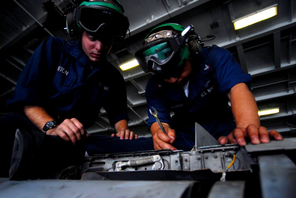 US Navy 070403-N-2659P-054 Aviation Structural Mechanic Airman Joshua Burton, left, and Aviation Structural Mechanic 3rd Class Ricardo Pezaguirre work together to install a wingfold swivel on an F-A-18C Hornet