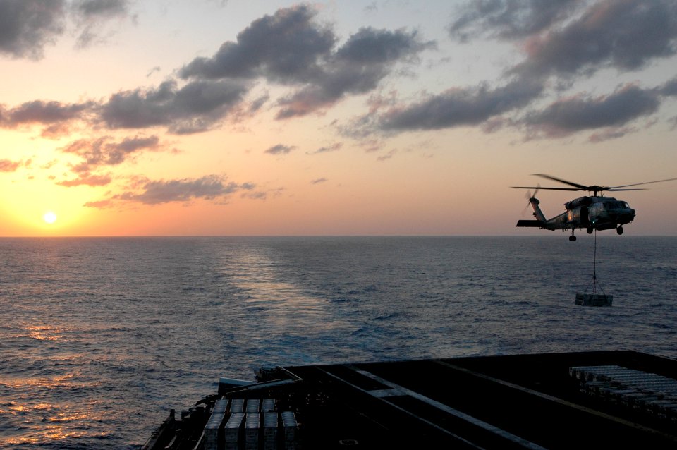 US Navy 070405-N-1635S-006 With the sun setting behind the aircraft carrier USS Ronald Reagan (CVN 76), an HH-60H Seahawk