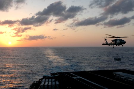 US Navy 070405-N-1635S-006 With the sun setting behind the aircraft carrier USS Ronald Reagan (CVN 76), an HH-60H Seahawk