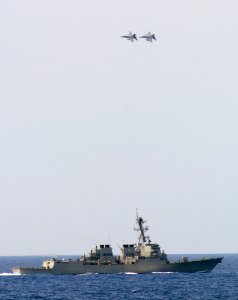 US Navy 070403-N-5345W-171 Two F-A-18F Super Hornets from the Red Rippers of Strike Fighter Squadron (VFA) 11 bank hard in formation over the Arleigh Burke-class guided missile destroyer USS Oscar Austin (DDG 79)