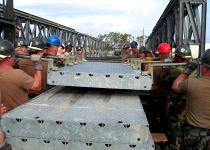 US Navy 070405-N-2374M-034 Seabees assigned to Naval Mobile Construction Battalion (NMCB) 24, and Naval Mobile Construction Battalion (NMCB) 27 lift a component of a Medium Girder Bridge into place during a bridge building clas