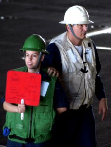 US Navy 070406-N-9712C-014 Boatswain's Mate Seamen Angie Jimenez signals to her counterpart on board Military Sealift Command (MSC) ammunition ship USNS Flint (T-AE 32)