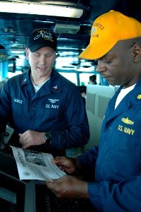 US Navy 070403-N-7128A-002 Aerographer's Mate 2nd Class Ryan Sorge, left, updates Office of the Deck, Lt. Cmdr. Joseph Baxter, on current weather conditions for flight operations aboard the nuclear-powered aircraft carrier USS