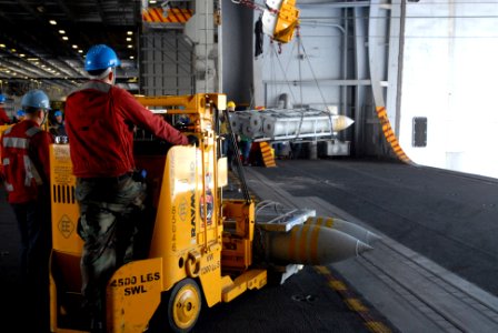 US Navy 070406-N-2959L-678 Weapons department personnel watch as ordnance is lifted by a sliding pad eye in the hanger bay of Nimitz-class aircraft carrier USS Ronald Reagan (CVN 76)