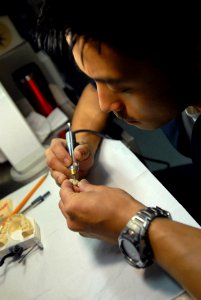 US Navy 070406-N-2959L-137 Hospital Corpsman 2nd Class Noel Toledo, from San Diego, Calif., carefully shapes a set of dentures aboard the aircraft carrier USS Ronald Reagan (CVN 76) photo