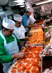 US Navy 070406-N-2959L-756 Members of USS Ronald Reagan (CVN 76) First Class Association prepare and put toppings on pizzas in the galley as part of a special dinner prepared for the crew