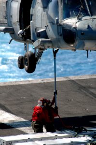 US Navy 070405-N-1635S-002 Aviation Ordnancemen attach the pendant on a hoisting sling to the external hook of a HH-60H Seahawk