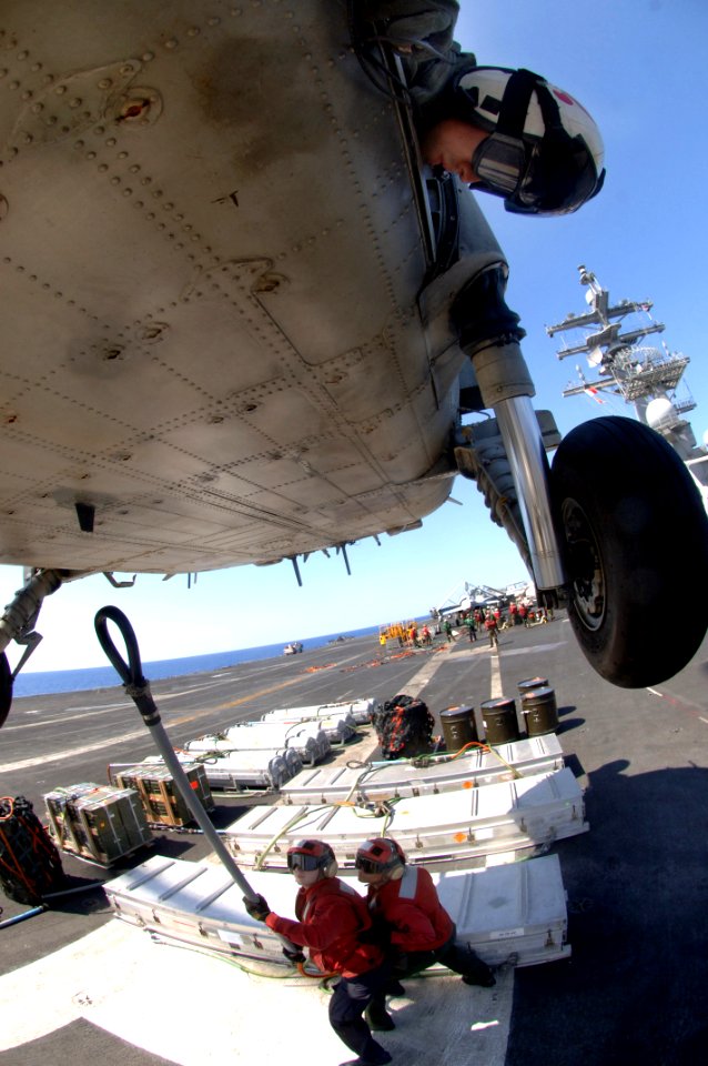 US Navy 070406-N-5961C-006 Aviation Warfare Systems Operator 2nd Class Anthony Chavez directs the SH-60 in closer to pick up a load of munitions aboard the Nimitz-Class aircraft carrier USS Ronald Reagan (CVN 76)