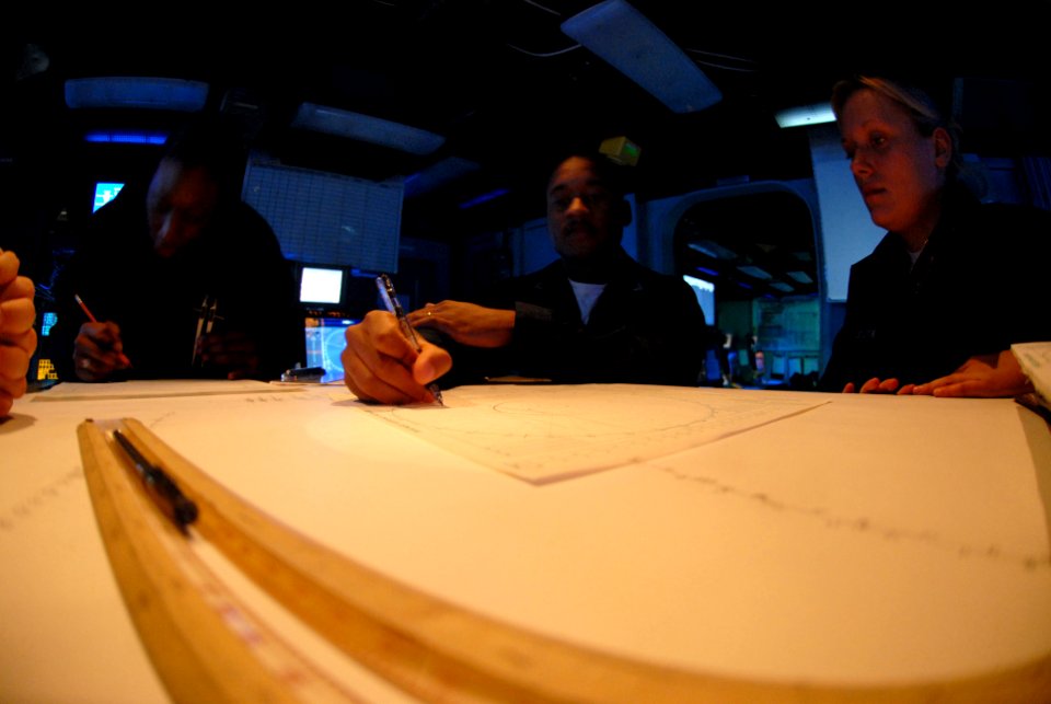 US Navy 070406-N-7730P-068 Operations Specialist 2nd Class Domonique Bibbs trains Seaman Larissa Stanczak on how to fill out a maneuvering board (MOBOARD) in the Combat Direction Center (CDC)