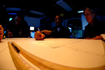 US Navy 070406-N-7730P-068 Operations Specialist 2nd Class Domonique Bibbs trains Seaman Larissa Stanczak on how to fill out a maneuvering board (MOBOARD) in the Combat Direction Center (CDC)