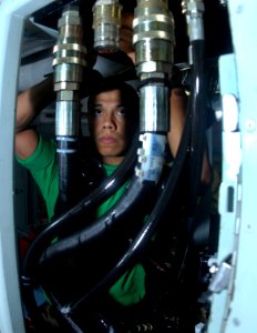 US Navy 070409-N-3038W-002 Aviation Structural Mechanic 3rd Class Rene Tovar adjusts a connection point on a fixture hydraulic supply servo cylinder test station in the hydraulics shop aboard the Nimitz-class aircraft carrier U photo