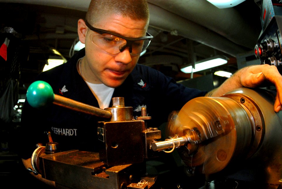 US Navy 070413-N-3038W-042 Machinery Repairman 3rd Class Anthony Gerhardt creates a guide pin for support equipment using a lathe in the machine shop aboard Nimitz-class aircraft carrier USS John C. Stennis (CVN 74)