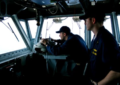 US Navy 070418-N-1328S-001 Ensign Casey Blount looks on as Lt. Todd Hastings uses a compass to help plot the course for amphibious assault ship USS Boxer (LHD 4)