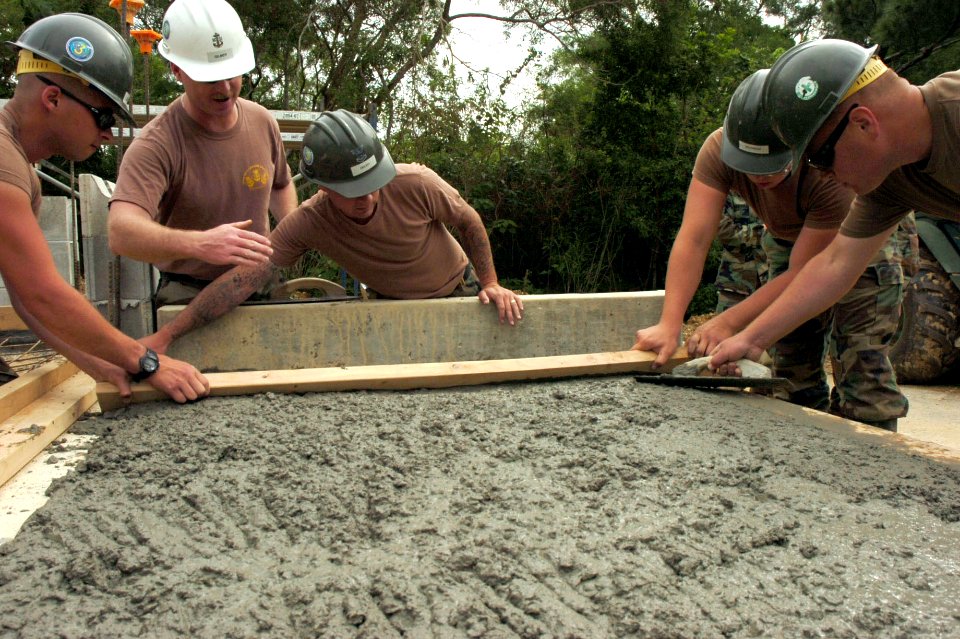 US Navy 070416-N-0775Y-004 Chief Builder Aaron Gilmer supervises Seabees from Naval Mobile Construction Battalion (NMCB) 3 as they use a two-by-four to level concrete during the construction of a storage facility at Camp Hansen