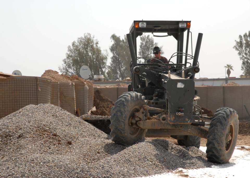 US Navy 070420-N-3560G-021 Equipment Operator 2nd Class Hayden Coleman assigned to Naval Mobile Construction Battalion (NMCB) 4 operates a grader, spreading gravel on a newly constructed parking lot