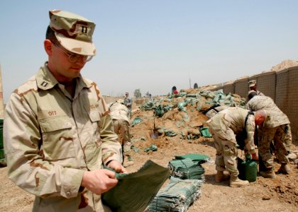 US Navy 070425-N-3560G-015 Navy Chaplain, Lt. Peter Ott, assigned to Naval Mobile Construction Battalion (NMCB) 4 lends a hand filling sandbags for various construction projects