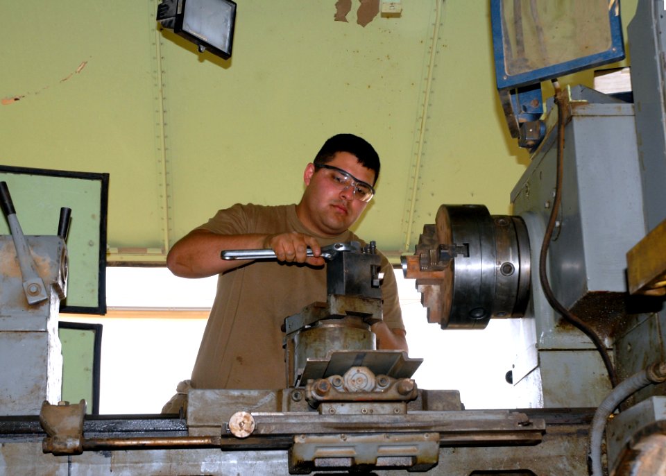 US Navy 070426-N-3560G-007 Machinery Repairman 3rd Class Christian Duarda of Naval Mobile Construction Battalion (NMCB) 4 adjust the cutting angle on a portable lathe