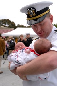 US Navy 070420-N-9604C-004 Lt. Cmdr. Brad Donnely embraces his newborn son and daughter upon returning from a three-month surge deployment on board USS Ronald Reagan (CVN 76)