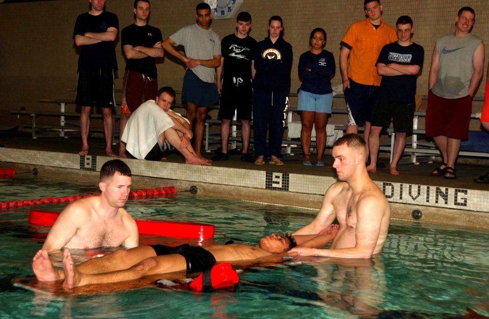 US Navy 070418-N-2143T-002 Lance Cpl. Brandon Coulter, Marine Combat Water Survival Instructor (MCWSI), and Master-at-Arms 1st Class Edwards Wolfe, from Marine Security Forces (MSF), remove Hospital Corpsman 3rd Class Carlos Ag