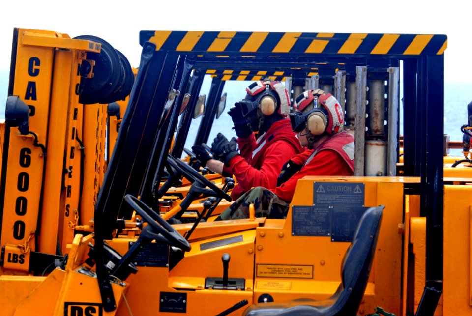 US Navy 070424-N-5484G-022 Aviation Ordnanceman 2nd Class James Tipton and Airman James Johnson sit in their forklifts in preparation to move cargo during a vertical replenishment (VERTREP) aboard nuclear-powered aircraft carri