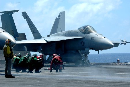 US Navy 070425-N-9760Z-036 Sailors duck to avoid the heat of the engine from an F-A-18E Super Hornet as it prepares to launch from aboard nuclear-powered aircraft carrier USS Nimitz (CVN 68)