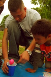 US Navy 070421-N-4124C-028 Gunner's Mate 3rd Class Eric Young, assigned to USS Juneau (LPD 10), helps Japanese children of the foster care facility Koyoryo Children's Home decorate an Easter egg as part of a visit