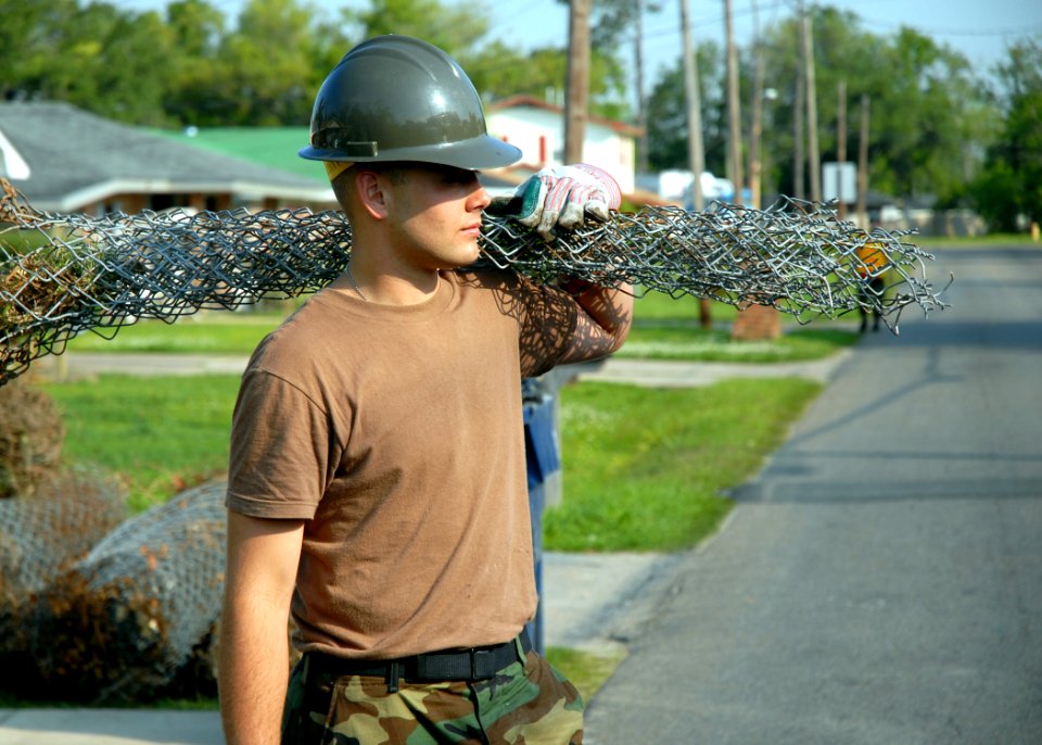 US Navy 070501-N-7367K-004 Construction Electrician Constructionman Recruit Darrel Fincher Jr., a Seabee with Naval Mobile Construction Battalion Seven (NMCB) 7, carries rolled fencing to a dump truck
