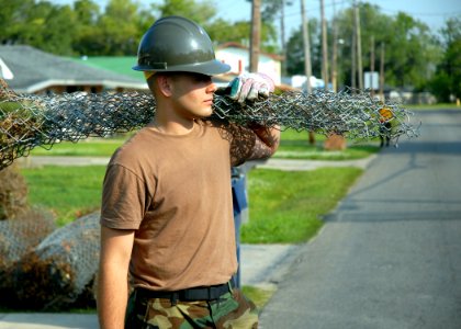 US Navy 070501-N-7367K-004 Construction Electrician Constructionman Recruit Darrel Fincher Jr., a Seabee with Naval Mobile Construction Battalion Seven (NMCB) 7, carries rolled fencing to a dump truck