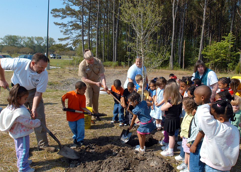 US Navy 070425-N-1082Z-003 Area forester for the Va. Department of Forestry, Jack Kauffman, along with Naval Air station (NAS) Oceana Commanding Officer Capt. Patrick Lorge help children shovel dirt around a tree planted at Oce