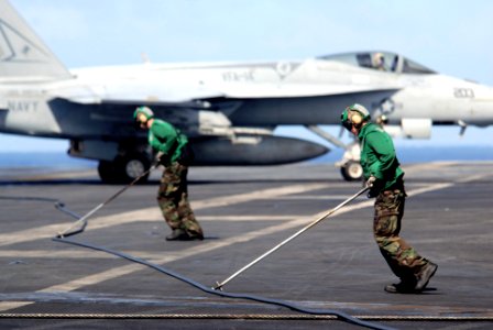 US Navy 070426-N-5484G-059 Aviation Boatswain's Mates Airman Garrett Metcalf and Billy Black push the arresting cable as it recoils after stopping an F-A-18E Super Hornet, assigned to the Tophatters of Strike Fighter Squa