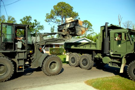US Navy 070501-N-7367K-007 Equipment Operator 2nd Class Seth Vaughn, a Seabee with Naval Mobile Construction Battalion (NMCB) 1, loads debris onto a dump truck photo