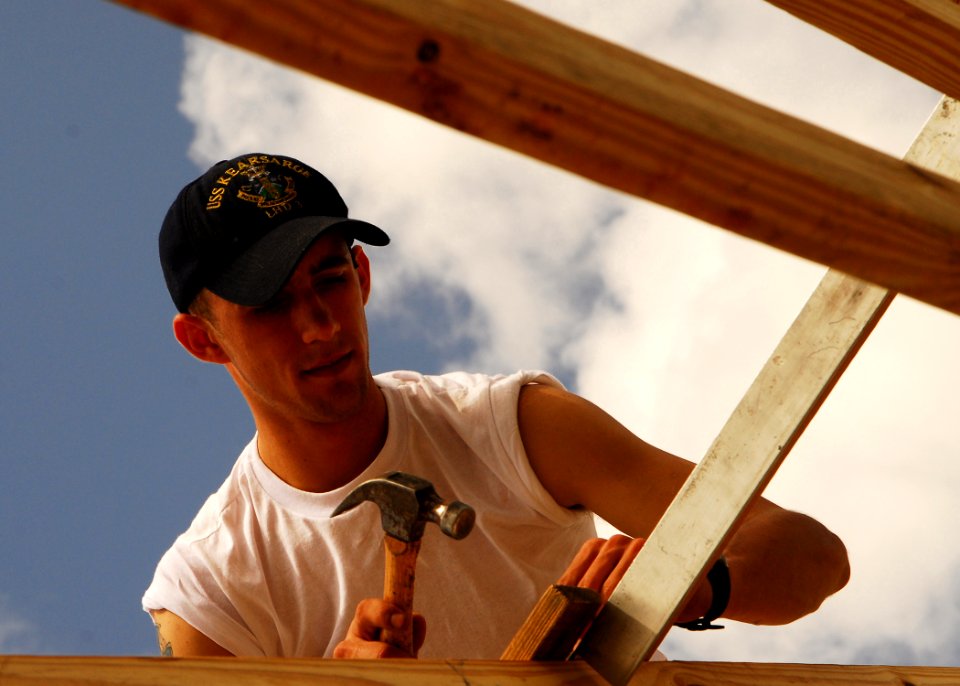 US Navy 070503-N-1831S-152 Aviation Support Equipment Technician Airman Kyle Blake nails a two by four to a roofing frame during a community relations project