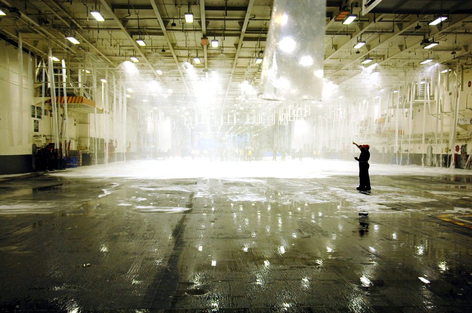 US Navy 070504-N-7883G-052 Engineering and air department Sailors observe tests of the aqueous film forming foam (AFFF) fire suppression system in hangar bay 1 on USS Kitty Hawk (CV 63)