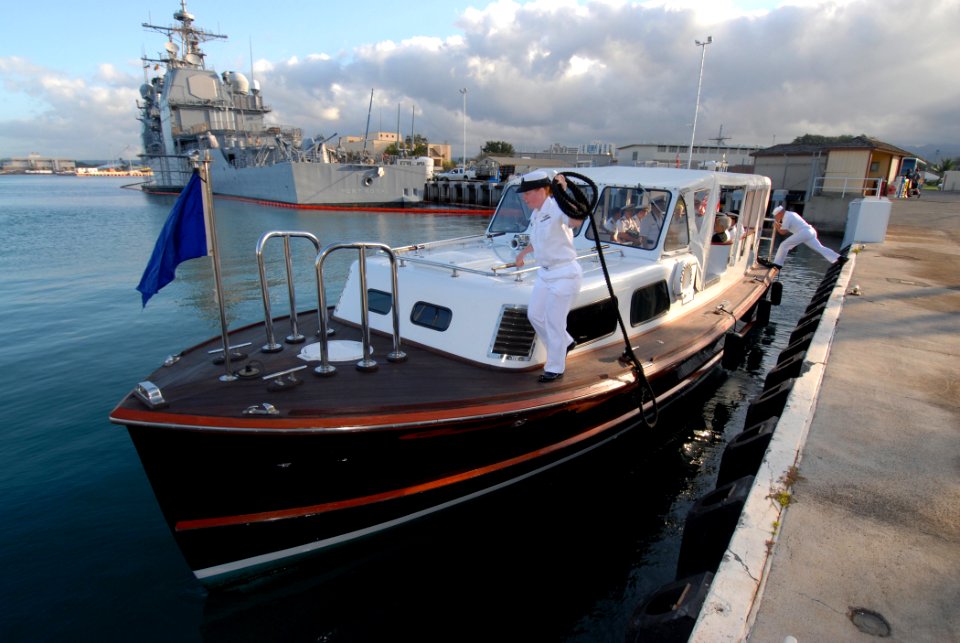 US Navy 070503-N-4965F-005 Boatswain's Mate 2nd Class Veronica Green pulls in a mooring line as Engineman 1st Class Joshua Schultz, both assigned to Commander, Navy Region Hawaii barge crew, pushes off
