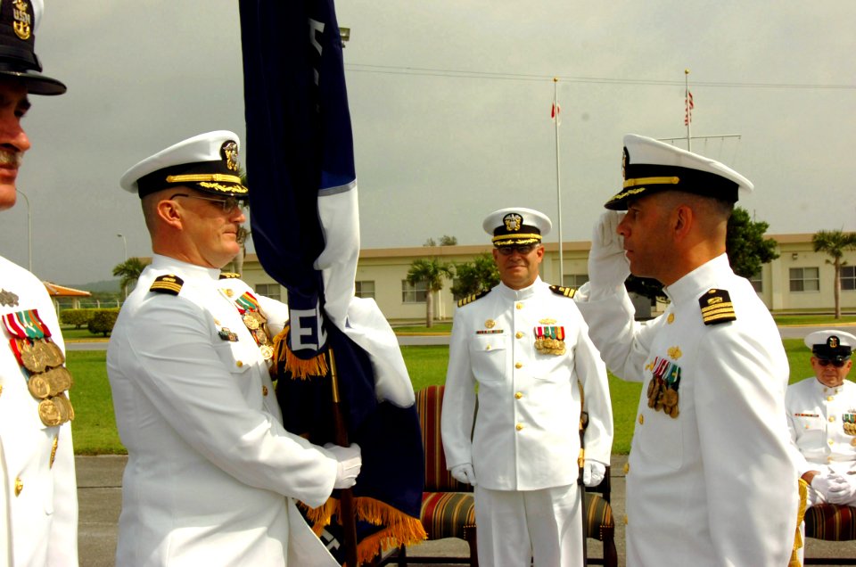 US Navy 070504-N-4198C-006 Cmdr. Tony M. Edmonds salutes Cmdr. Scott K. Higgins as he passes the battalion's flag during the change of command ceremony for Naval Mobile Construction Battalion (NMCB) 3 at Camp Shields, Oki