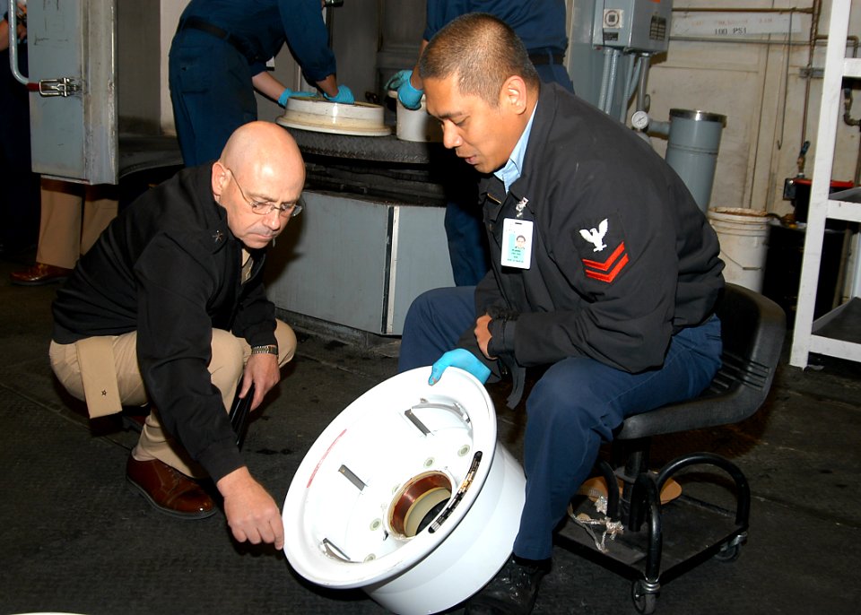 US Navy 070503-N-6247M-005 Aviation Structural Mechanic 2nd Class Mustapha Plang, from Manila, Philippines explains to Rear Adm. Michael Hardee, commander Fleet Readiness Centers, how he is building up the balancing mark on a t