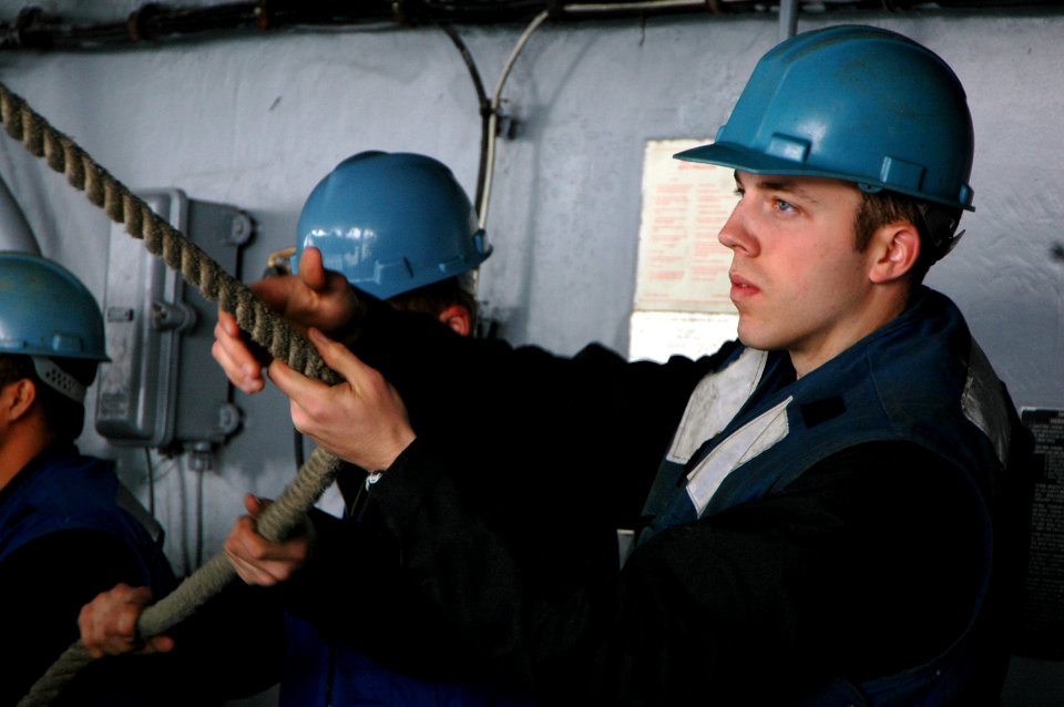 US Navy 070501-N-7883G-063 Boatswain's Mate Seaman Brent Webster from Rapid City, S.D., holds onto a line while lowering the rigid hull inflatable boat during a man overboard drill on USS Kitty Hawk (CV 63)