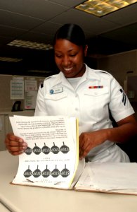 US Navy 070503-N-2143T-003 Personnel Specialist Seaman Apprentice Kimberly Mcghee verifies a Sailor's service record to ensure proper documentation is complete before filing records at the Naval Base Kitsap Personal Suppo