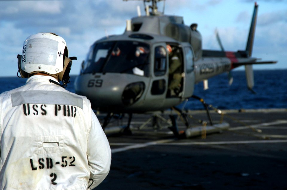 US Navy 070505-N-7029R-050 Boatswain's Mate 1st Class Everett Albright, flight safety operator, over looks flight deck operations while a Brazilian navy helicopter awaits take off from USS Pearl Harbor (LSD 52) during UNI
