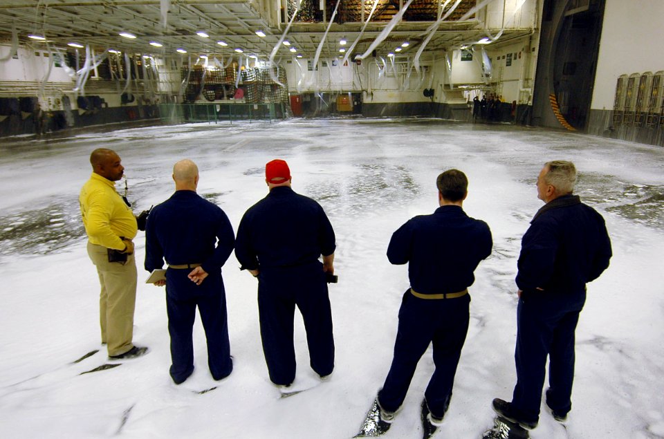 US Navy 070504-N-7883G-048 Engineering and air department Sailors observe tests of the aqueous film forming foam (AFFF) fire suppression system in hangar bay 1 on USS Kitty Hawk (CV 63)
