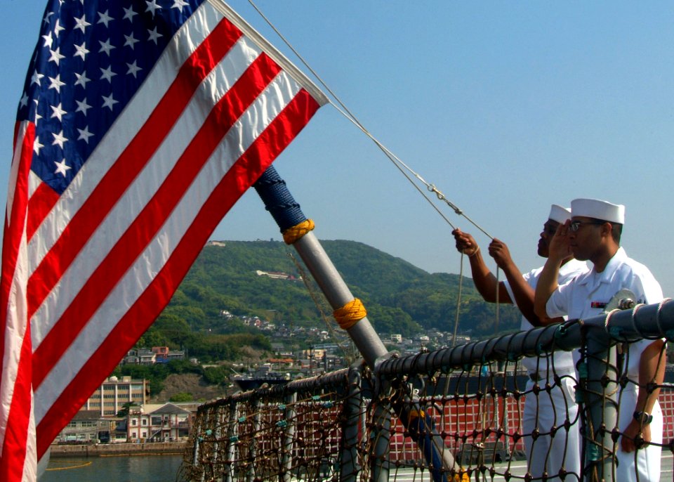 US Navy 070511-N-0120A-050 Storekeeper Seaman Kirt Q. Hicks salutes the Ensign as Storekeeper Seaman Mathew King lowers it, as a part of the sea and anchor detail in preparation for getting underway