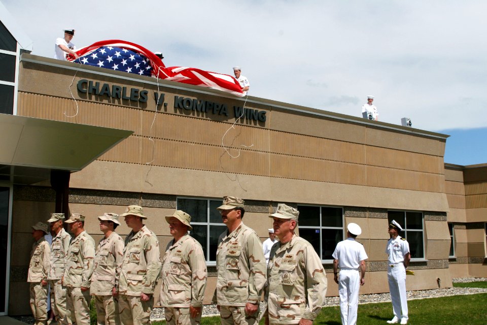 US Navy 070508-N-0975R-001 Seabees from Naval Mobile Construction Battalion (NMCB) 18 stand by while the ensign is lifted to reveal the newly named Charles V. Komppa wing in honor of the Seabee that died in Iraq, Oct. 25, 2006