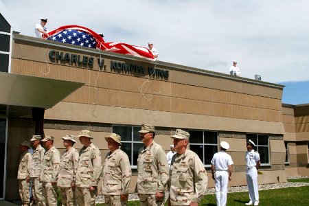 US Navy 070508-N-0975R-001 Seabees from Naval Mobile Construction Battalion (NMCB) 18 stand by while the ensign is lifted to reveal the newly named Charles V. Komppa wing in honor of the Seabee that died in Iraq, Oct. 25, 2006
