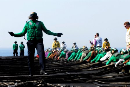 US Navy 070512-N-3729H-076 Aviation Boatswain's Mate (Equipment) 3rd Class Trevino Crowder directs flight deck personnel working together to rig the aircraft barricade aboard the Nimitz-class aircraft carrier USS John C. Stenni