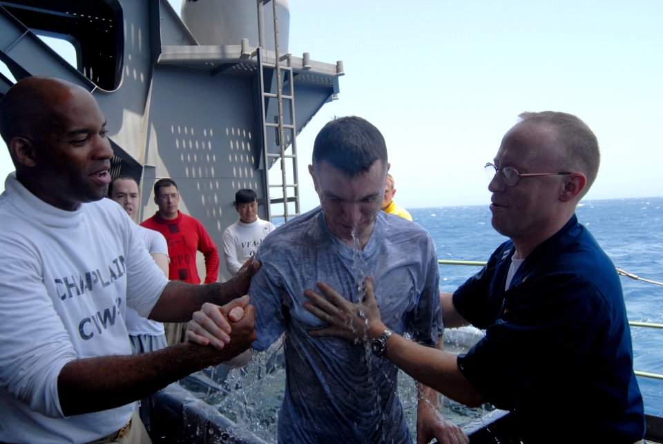 US Navy 070513-N-3038W-053 Chaplains, Lt. Anthony Carr (left) and Lt. Scott Callaham baptize Airman Christopher Allington on the fantail of the Nimitz-class aircraft carrier USS John C. Stennis (CVN 74)
