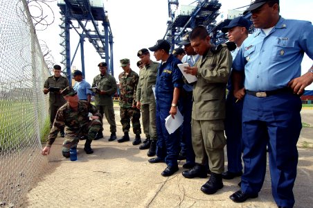 US Navy 070509-N-0989H-030 Master-at-Arms Chief Robert Hewitt points out a security risk in the fence surrounding Pier 6 to Panamanian National Maritime Service and Police members