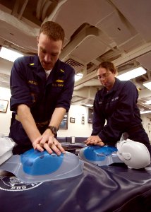 US Navy 070515-N-5253W-001 Ensign Michael Miller (left) and Seaman Deana Hakes assigned to the Arleigh Burke-class guided-missile destroyer USS Lassen (DDG 82) practice chest compressions on mannequins during cardio-pulmonary r