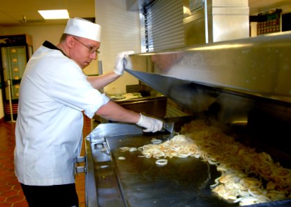 US Navy 070510-N-7656R-001 A culinary specialist grills onions while preparing lunch for Sailors at the Trident Inn on Naval Base Kitsap Bangor