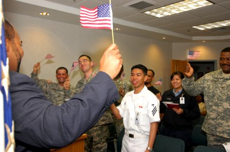 US Navy 070515-N-9134V-011 Active duty Sailors and Soldiers proudly wave their flags in celebration of becoming America's newest citizens during a naturalization ceremony