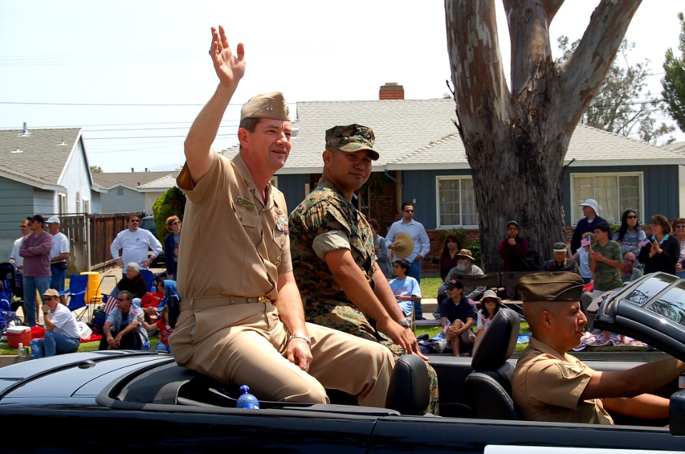 US Navy 070519-N-9706M-003 Purple Heart recipient Hospital Corpsman 2nd Class Ivan H. Delfin sits next to Commander, Navy Region Southwest Rear Adm. Len R. Herring who waves to the crowd lining the streets near the grandstand